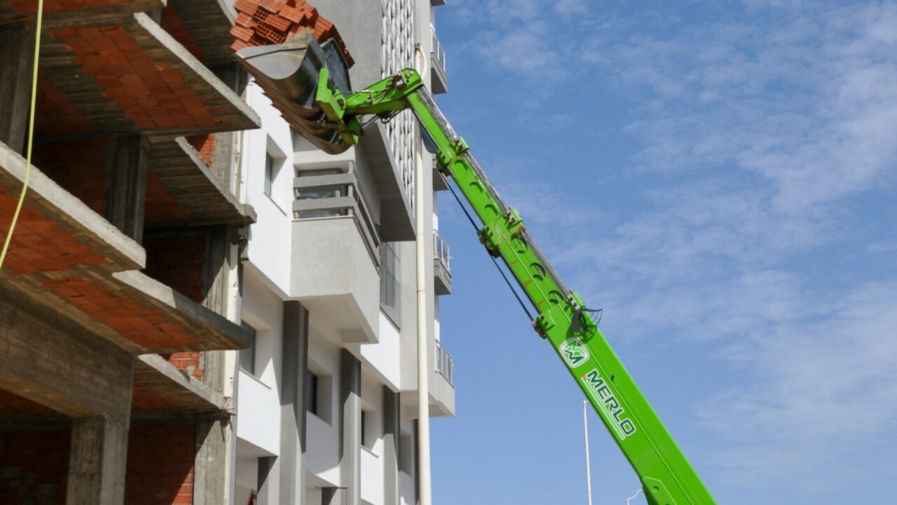 Ładowarka teleskopowa podnosząca palety cegieł na budowie domu
