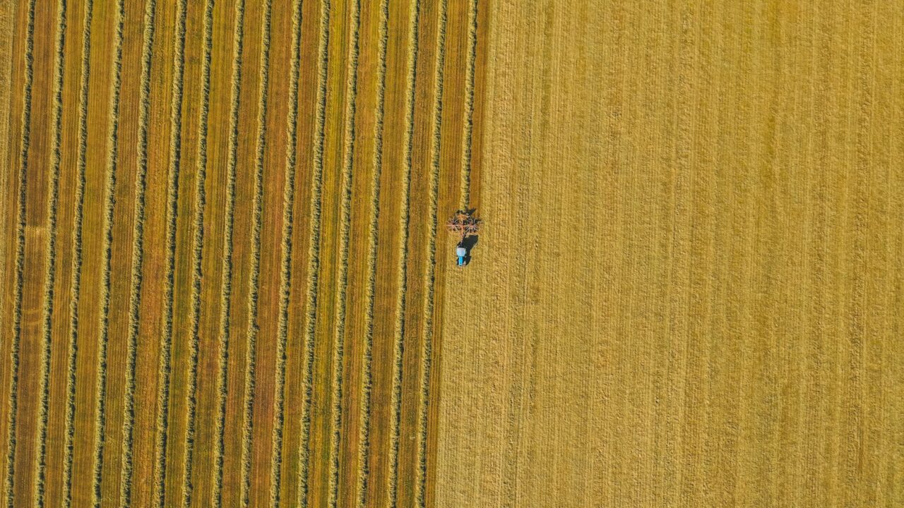 Widok z lotu ptaka na pole uprawne z pracującym ciągnikiem